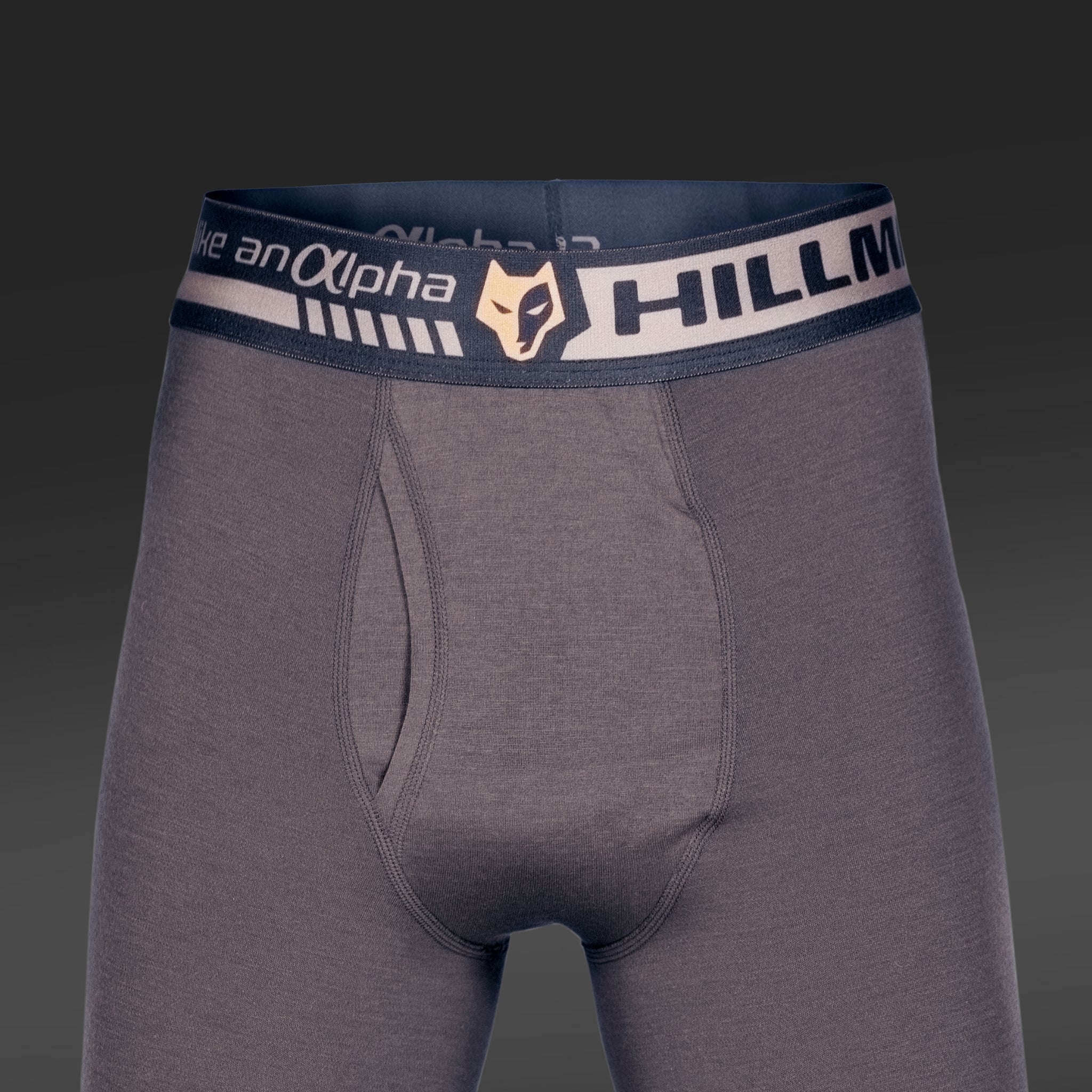 Imagine a boxerului Hillman gri închis pentru bărbați, cu o talie neagră, cu accente gri/bej, text „HILLMAN” și un logo animal. Fabricat din Lenjerie Termică din Lână Merino pentru o reglare optimă a temperaturii și confort pe tot parcursul zilei.